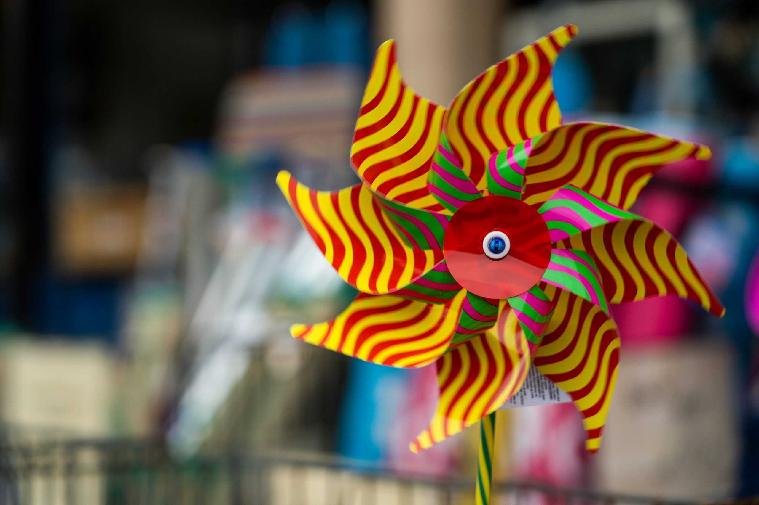 a vibrant pinwheel with yellow an pink stripes and a blurred background